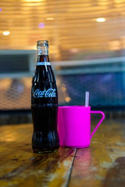 Bangkok, Tayland - 16 Ekim 2024 Restoranda üzerinde pembe bardak olan bir şişe Cold Coca Cola