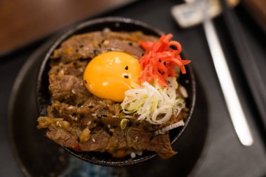 Wagyu bifteği pilavı ve çiğ yumurta kasesi, kremalı yumurta sarısı leziz bifteği kucaklıyor, dokuların ve tatların lezzetli bir harmonisine karışıyor siyah bir kasede..