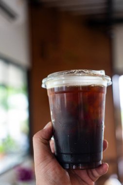 Kahve dükkanında elinde buzlu kahve tutan bir adam.