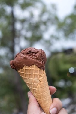 Çikolatalı dondurmalı waffle külahı tutan adam.