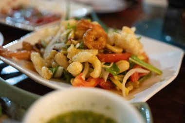 Taze sebzeli Tayland salatası, deniz ürünleri ve çıtır tavuk derisi. Kapat.