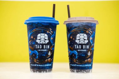 Bangkok, Thailand - November 11, 2024 : Hand holding a cup of Tao Bin beverage, Tao Bin Beverage Is created fresh coffee and soft drink vending machines maker. clipart