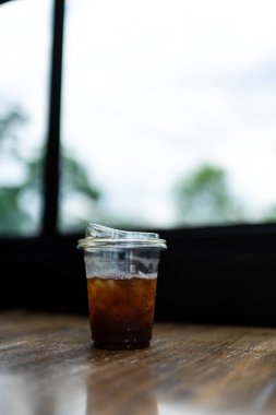 Tahta masada şeffaf plastik bir fincanda buzlu kahve içtikten sonra.