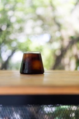 Soğuk demlenmiş kahve, sabah berrak bir bardakta, ahşap masada.