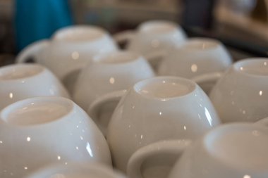 Seramik kahve fincanları bir kafedeki kahve makinesinin üzerinde baş aşağı duruyor.