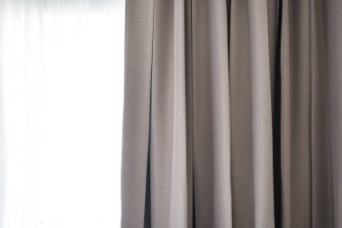 Pencerede parlak, kahverengi perdeler ve güneş ışığı.