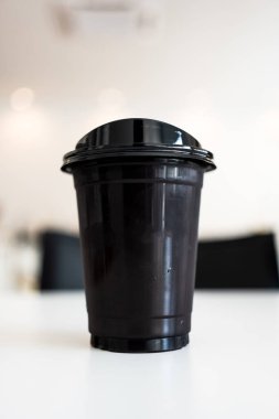 Siyah kapaklı bir fincan buzlu Americano kahvesi, kapağıyla içebilirsin.