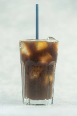 Buzlu sade kahve, bardakta buz ve mavi pipet.