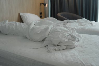 Beyaz buruşuk battaniye yastıklı yatak. Sabah otel odasında yapılmamış yatak.