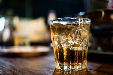 Ahşap masada buzlu viski bardağı.