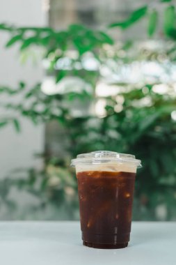 Plastik fincanın üzerine koyu soğuk americano kahvesinin seçici odağı bulanık arka plan, minimal kafede fotokopi alanı. İçki ve Kafein İçeceği.