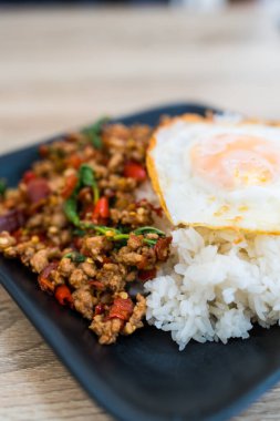 Tayland usulü kızarmış fesleğen, kıymalı domuz eti ve kızarmış yumurta ile pilav ve Tayland yemeği. Pad Kaprao Moo Kai Dao