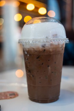 Masanın üzerinde plastik bardakta buzlu kahve.