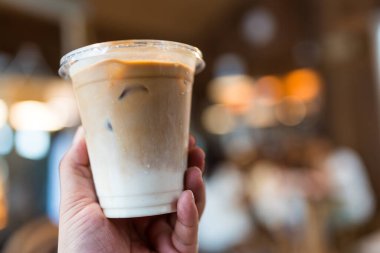 Adam elinde plastik bir bardak buzlu kahve tutuyor.