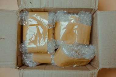 Paket beyaz baloncuk ambalajı ve kahverengi yapışkan bantla sarılmış.