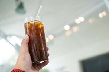 Elinde şeffaf bardakta buzlu sade kahve. Yaz için ferahlatıcı içecek.