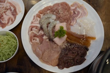 Tayland usulü çiğ domuz eti ya da Tayland usulü barbekü ızgarası ya da restoranda Moo Krata için marine edilmiş deniz ürünleridir. Bir set Tayland yemeği Moo krata ve malzemeleri.