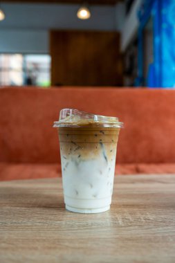 Plastik bir bardak buzlu kahve, üst katmanda espresso, daha aşağıda taze süt.
