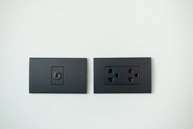 Siyah elektrik prizi ve anten kablosunu TV prizine yerleştirir. Siyah elektrik düğmeli modern iç tasarım elementi