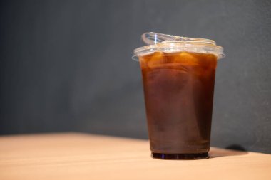 Paket servis bardağında buzlu kahve. Tahta masada.