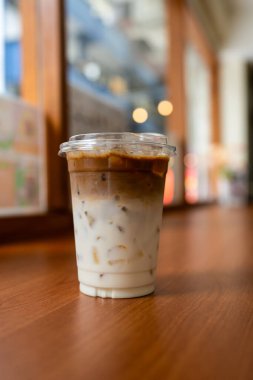 İki katlı buzlu kafe latte, espresso ve ahşap masada taze süt.