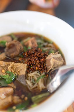 Et ve sebzelerle dolu, yemek ya da öğle yemeği için uygun, siyah ahşap bir masada, dumanı tüten erişte çorbası.