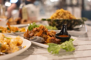 Sarımsaklı yumuşak kabuklu yengeç ve masada bir sürü deniz ürünü.