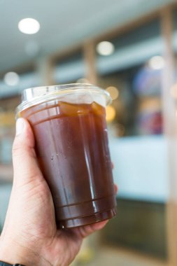 Kahve dükkanında bir fincan buzlu kahve tutarken.