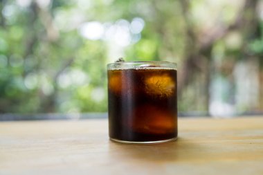 Tahta masadaki mini bardakta nefis siyah buzlu kahve. Kapat.