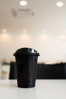 Siyah kapaklı bir fincan buzlu Americano kahvesi, kapağıyla içebilirsin.