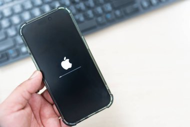 Bangkok, Tayland - 25 Aralık 2024: iOS yazılımı en son sürümüne güncellenirken iPhone, iphone ekranında yükleme çubuğu olan Apple simgesi.