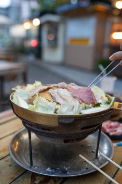 Domuz etini ve diğer eti al ve çok sıcak bir tavaya koy. Taze sebzeler çorbayla birlikte tavada kaynatılır. Thai barbekü ızgarası Sıcak tavada domuz eti.