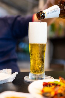 Bangkok, Tayland - 30 Aralık 2024: Singha birasını restorandaki masada soğuk bardaklara dolduran adam