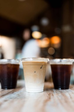 Görüntüyü kapat. Ortaya bir bardak buzlu latte koy. Buzlu sade kahve, masa arkaplanı bulanık olsun.