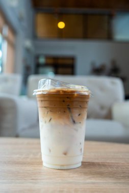 Plastik bir bardak buzlu kahve, üst katmanda espresso, daha aşağıda taze süt.