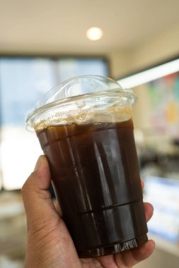 Yakın plan buzlu americano kahvesi ve plastik saman.