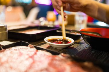 Elçi, ahşap çubukları karıştırır ve sosu karıştırır. Açık hava restoranında Tayland usulü sıcak tencere yemek için.