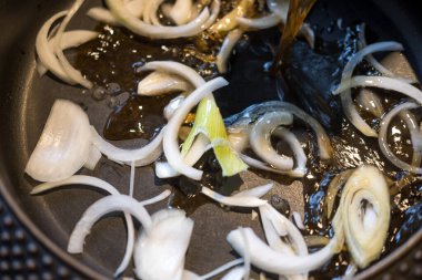 Sukiyaki pişirmek için siyah siyah tavada siyah çorba ile çiğ soğan.