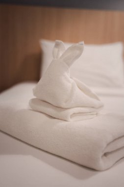 Havluya konmuş havludan yapılmış tavşan ve otel odasındaki yatak..