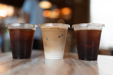 Üç sıra plastik kahve ve kahve dükkanındaki buzlu kahve fincanı ve buzlu kahve.