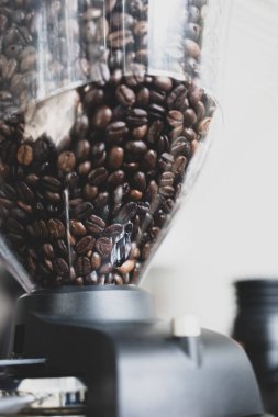 Kahve dükkanındaki elektrikli kahve öğütücüsünde taze kahve çekirdeği.