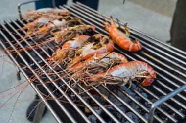 Tay nehri karidesleri kömür ızgarasının üzerinde ızgarada kızartılıyor ve iki tarafı da eşit derecede pişiriliyor. Tayland yemeğinin çok lezzetli bir parçası..
