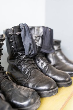 Rafta bağcıkları olan tozlu deri savaş ayakkabıları.