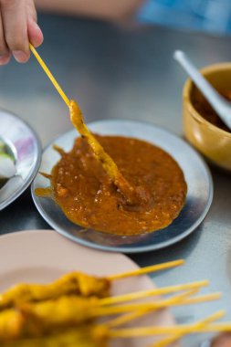 Sarı baharatla marine edilmiş satay domuz eti yemek restoranda tatlı fıstık sosu daldırmak..