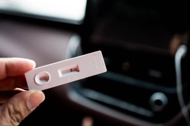El ele tutuşan antijen test kiti şeridi veya ATK negatif sonuç ile araba, covid-19 kendini hızlı test kavramı