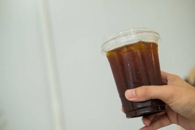 Kahve dükkanında elinde buzlu kahve tutan bir adam.