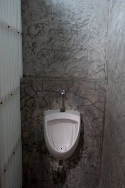 Erkekler tuvaletindeki beyaz pisuarlardan birinin tavan arası beton duvarındaki tuvaletteki beyaz seramik pisuarların tasarımı. Çatı katı biçimi