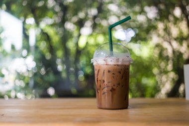 Tahta masaya konmuş şeffaf plastik bardakta buzlu kakao içeceği. Yazın serin tatlı içmek için lezzetli görünüyor.