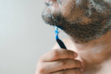 Evde tıraş olurken tıraş olan ciddi bir adam.