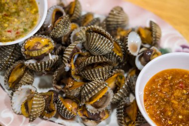 Lezzetli taze ve lezzetli haşlanmış midyeler ya da baharatlı deniz ürünleri sosuyla yenmiş midyeler..